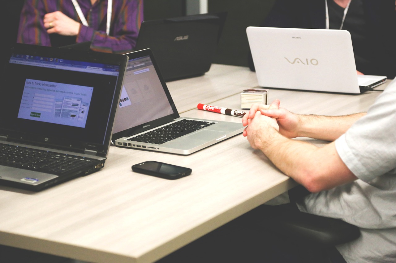 Personas reunidas alrededor de una mesa de trabajo con computadores portátiles